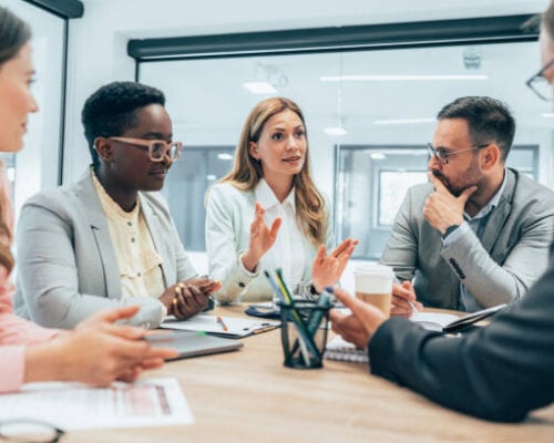 Modern business team discussing new ideas at the office. Business people on meeting in modern office. Colleagues smiling and talking at board room. Brainstorming